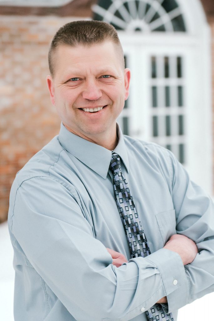 Man Smiling with a blue shirt and tie on