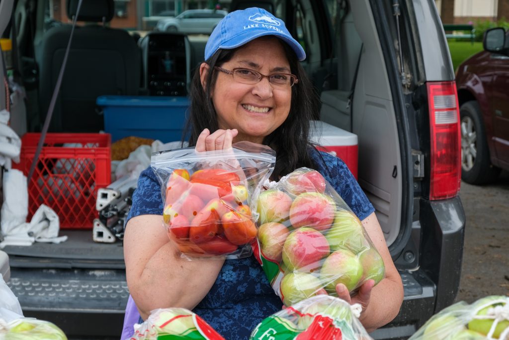 Woman wearing a blue hat holding apples and smiling