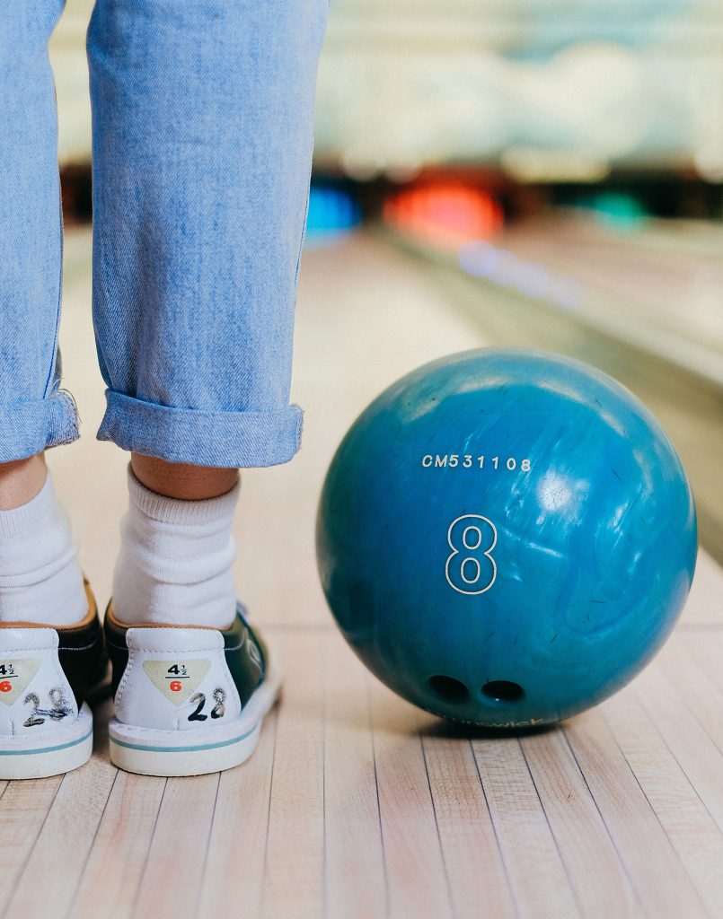 Bowling ball near feet with bowling shoes